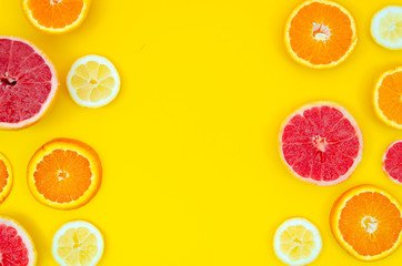 Flat lay Frame made of fresh lemon, orange and grapefruit slices on yellow background. Summer fresh vitamins concept