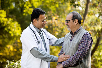 Doctor talking with senior man in hospital garden