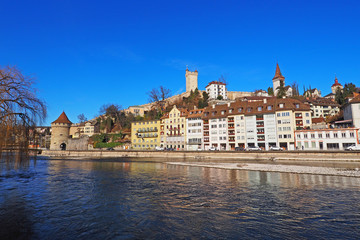 Fototapeta na wymiar Lucerne along Reuss River with medieval city wall and towers against deep blue sky.