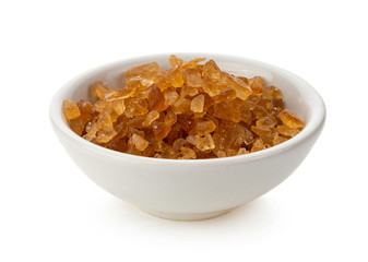 Brown rock sugars in bowl on white background