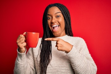 Young african american girl drinking a coffee cup over red isolated background very happy pointing with hand and finger