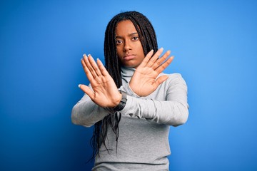 Young african american woman standing wearing casual turtleneck over blue isolated background...
