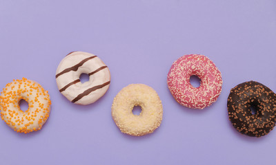 Delicious donuts on violet color background.