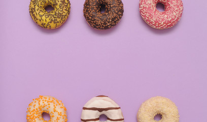 Delicious donuts on violet color background.