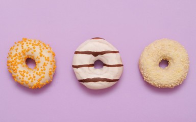 Delicious donuts on violet color background.