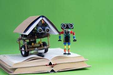 Hand made robot working on the arduino platform with books. Green background. Free space for text. STEM education for children and teenagers, robotics and electronics. DIY. AI. STEAM. Concept.