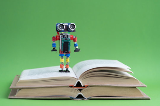 Hand made robot working on the arduino platform with books. Green background. Free space for text. STEM education for children and teenagers, robotics and electronics. DIY. AI. STEAM. Concept.