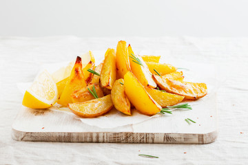 Homemade baked potato fries with rosemary on white wooden board