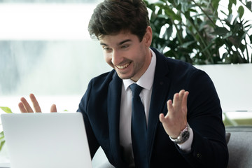 Excited surprised young businessman looking at laptop screen.