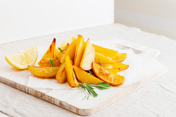 Homemade baked potato fries with rosemary on white wooden board