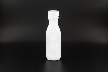 Plastic container mockup for inserting ads and any image. Bottle for storing liquid substances. White color with a white cover. Foreground. Isolated on a black background. Horizontal frame
