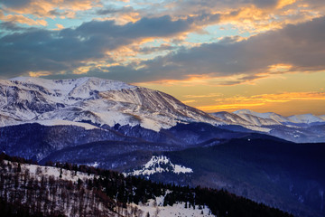 Naklejka na ściany i meble Sunset or sunrise panoramic view on stunning mountains. Winter scene with sunset in mountains.