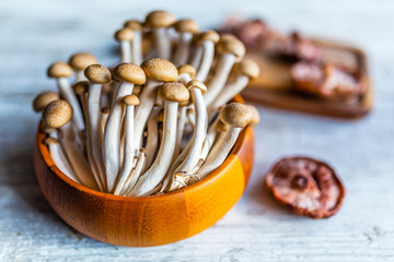 Fresh Shimeji and Shitake mushrooms on a wooden board.