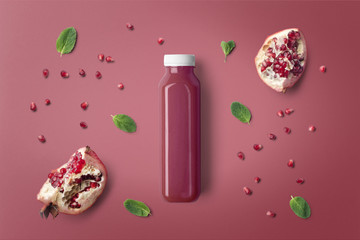 Pomegranate juice bottle mockup on purple background, with fruits and blank label to place your...