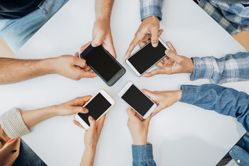 Unrecognizable friends using smartphones over table