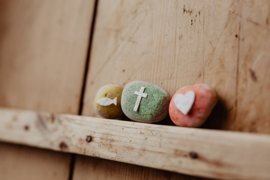 Kommunion, Konfirmation, Firmung, Taufe - bunte Steine mit Kreuz, Fisch und Herz auf Holz