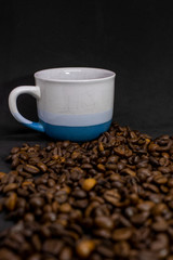 Coffee cup with grains against dark background. Close-up with copy space for your text.