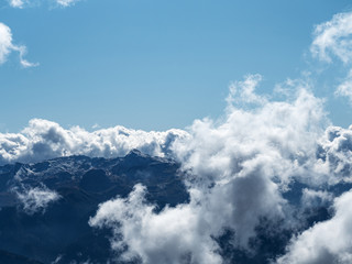 View of the tops of the mountains with clouds lying on them and a wide blue sky