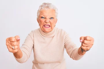 Fotobehang Senior grey-haired woman wearing turtleneck sweater standing over isolated white background angry and mad raising fists frustrated and furious while shouting with anger. Rage and aggressive concept. © Krakenimages.com