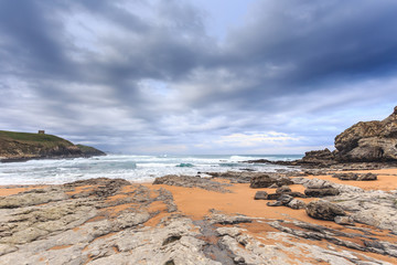 Fototapeta na wymiar Tagle beach in winter with dramatic sky and waves against the rocks