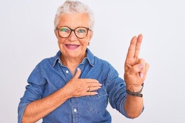 Senior grey-haired woman wearing denim shirt and glasses over isolated white background smiling...