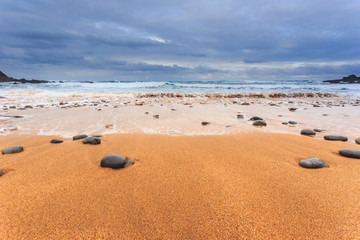 Tagle beach in winter with dramatic sky and waves against the rocks