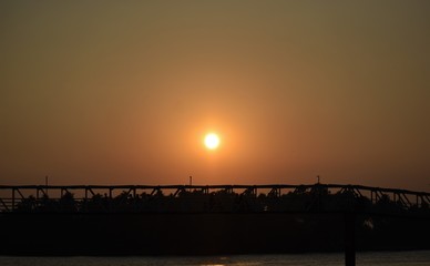 Silhouette of a bridge at dusk with beautiful sunset and red spread sky background