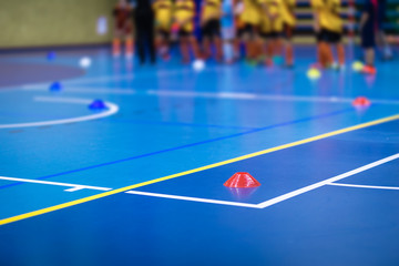 Sports team on futsal training field. Indoor soccer training during the winter. Futsal training field with blue cones. Indoor football practice for children. Physical education unit of soccer
