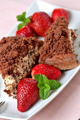 Homemade mole hole cake with whipped cream, banana, strawberries and fresh mint leaves on white decorative shaped plate. Pink place setting. Close-up.