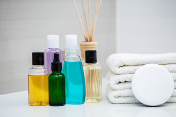 Cosmetic products and cotton towels on white wooden table in beauty salon