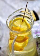 Glass jug with drink and chopped lemon