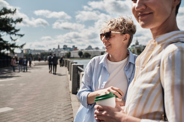 Two women walking outdoor with coffee