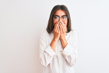Young beautiful businesswoman wearing glasses standing over isolated white background laughing and embarrassed giggle covering mouth with hands, gossip and scandal concept