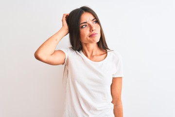 Young beautiful woman wearing casual t-shirt standing over isolated white background confuse and...