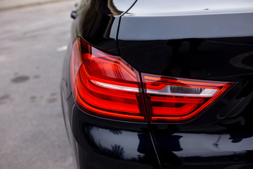 Rear view of a new black car. Close up of car headlights. Black premium urban crossover, luxury SUV rear light close up. Car lamp close-up