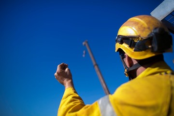 Trained rigger high risk worker wearing safety helmet commencing crane lifting signal by using...