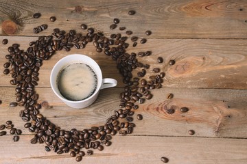 White mug of coffee surrounded by beans in wooden background, coffee concept