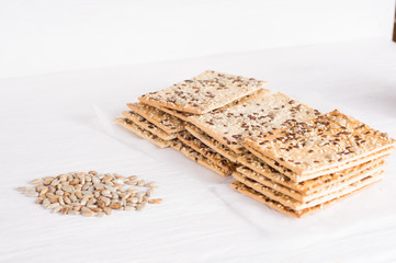 Stack of crispy wheat cakes with sesame seeds, flax and sunflower on a white wooden background. vegetarian food, eco food concepts