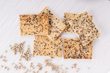 Stack of crispy wheat cakes with sesame, flax and sunflower seeds on white wooden background. Top view. vegetarian food, eco food concepts