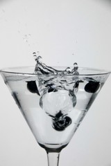 Blueberries splashing water into a cocktail glass on a white background