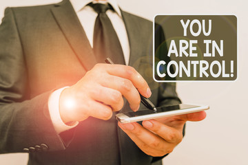 Writing note showing You Are In Control. Business concept for Responsibility over a situation Management authority Male human wear formal work suit hold smartphone using hand
