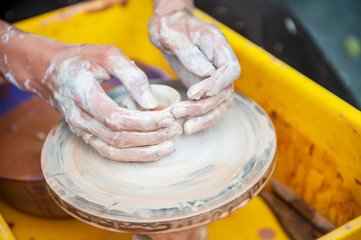 The potter makes pottery dishes on potter's wheel.