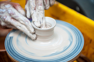 The potter makes pottery dishes on potter's wheel.