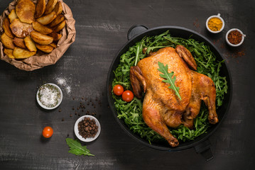 Roasted whole chicken or turkey served in iron pan Placed on black background Top view