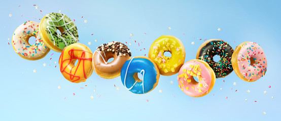 Various colorful doughnuts in motion on blue background