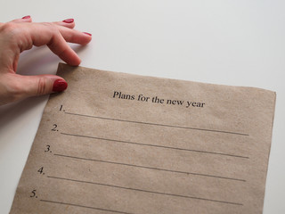 Plans for the new year. Text on Kraft paper. Female hand