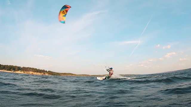 Riverbank with a man kiteboarding along it
