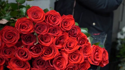 the flower seller is making a bouquet of red roses