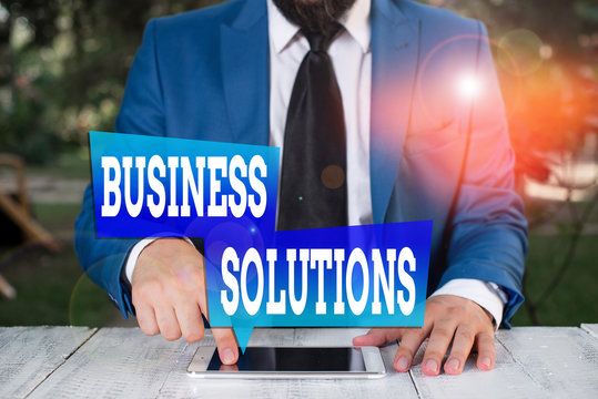 Word writing text Business Solutions. Business photo showcasing ideas used to help a company achieve its objectives Businessman in blue suite with a tie holds lap top in hands