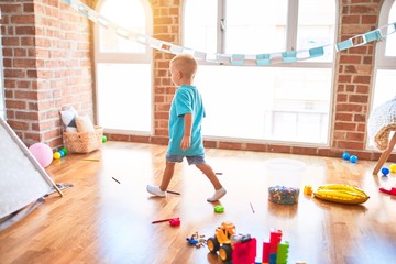 Young caucasian kid playing at kindergarten with toys. Preschooler boy happy at playroom.